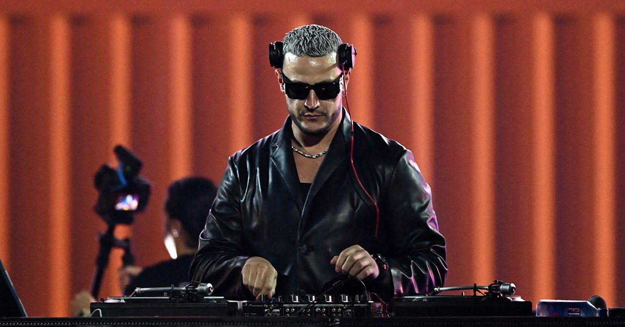 DJ Snake aux platines lors d'une performance scénique, casque sur les oreilles.