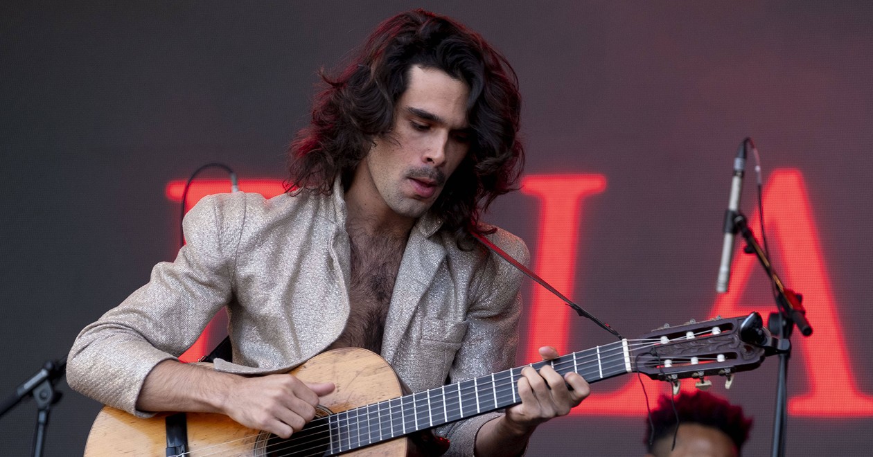Zé Ibarra en concert, guitare en main, sous les projecteurs.
